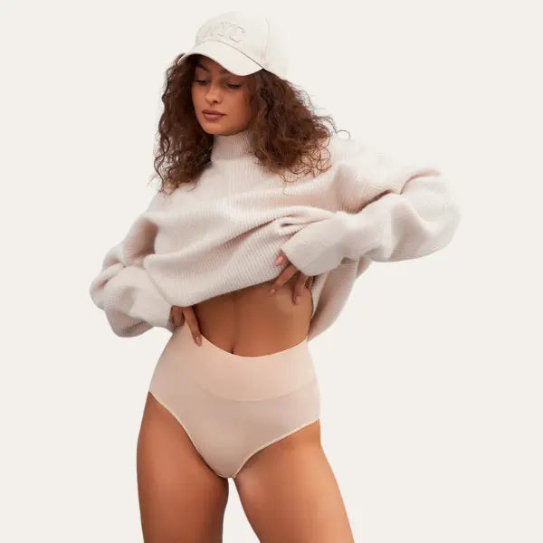 Modelo vestindo cuecas Pure bege de cintura subida com camisola oversized creme e boné