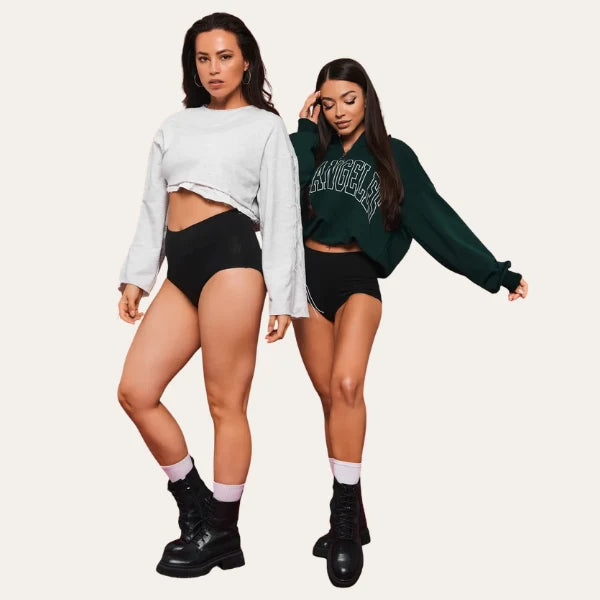 Duas modelos com Cuecas Pure Palum em Preto, cintura alta, com sweatshirts e botas pretas